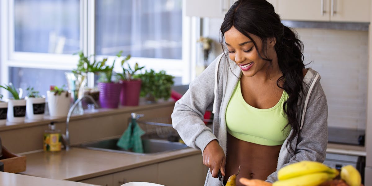 A person smiling and looking healthy while holding a piece of fruit.